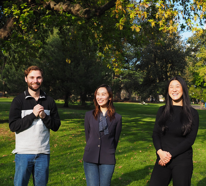 Three smiling colleagues stand outdoors