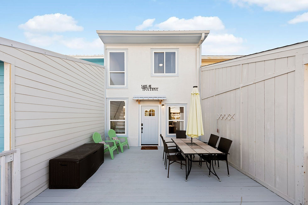 Outdoor patio at Short Stay Haven in Navarre Beach, featuring a dining table with chairs, lounge seating, and a private entrance under a clear blue sky.