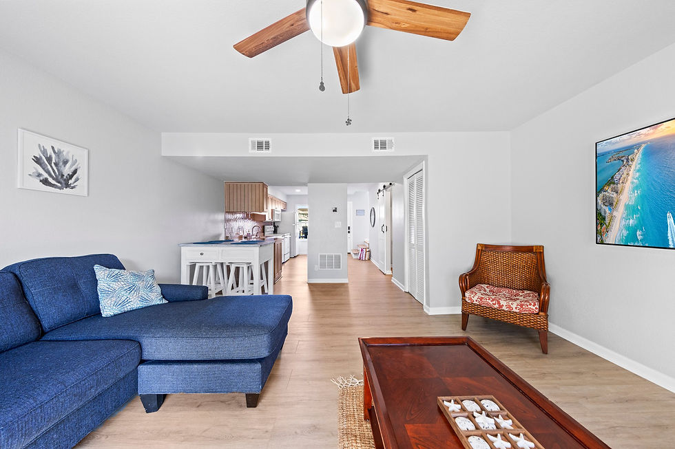 Bright and cozy living space at Short Stay Haven in Navarre Beach, featuring a comfortable blue sectional sofa, modern decor, and an open floor plan leading to the kitchen.