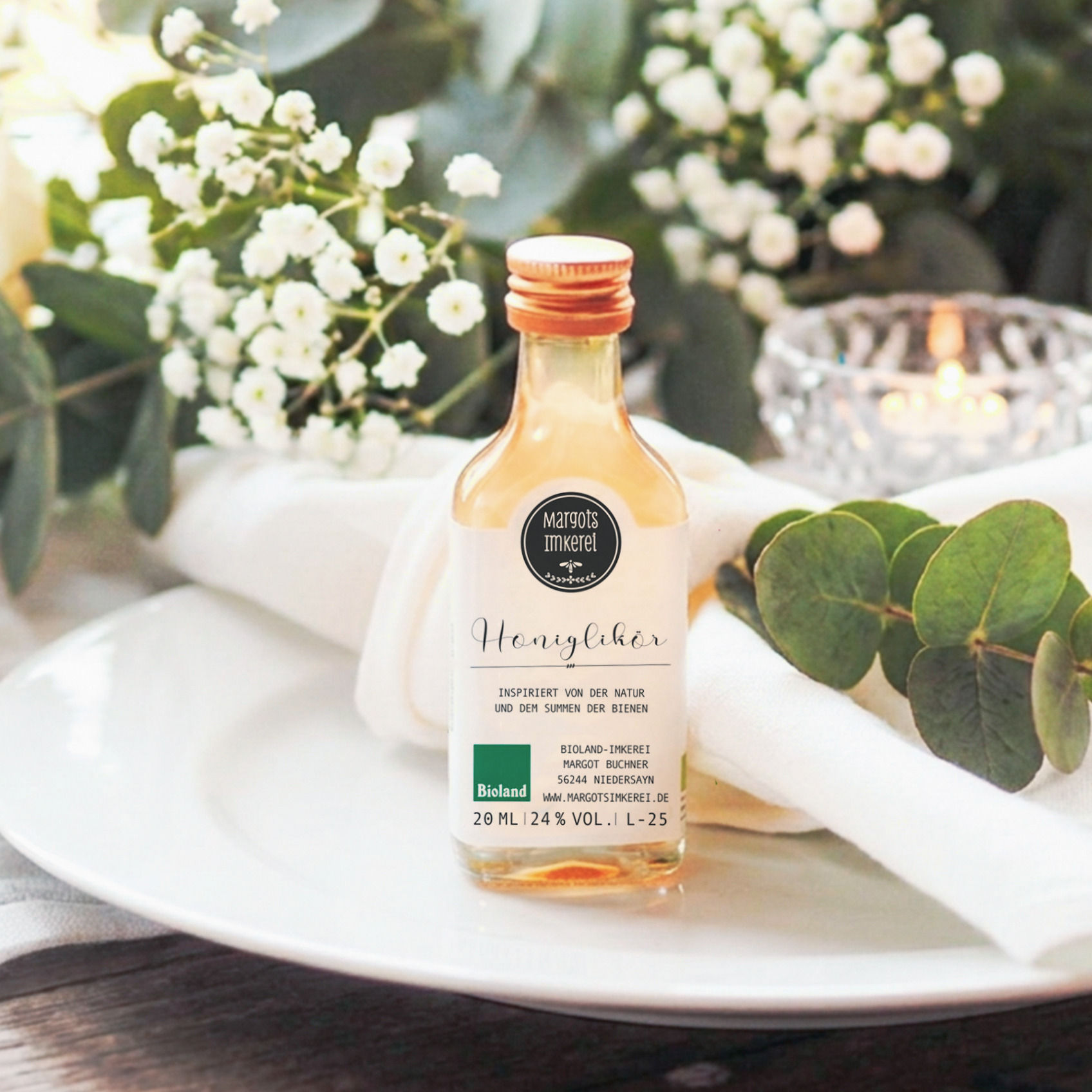 Honiglikör aus Margots Bioland-Imkerei als kleines Gastgeschenk auf Hochzeitstisch mit Eukalyptus und Schleierkraut
