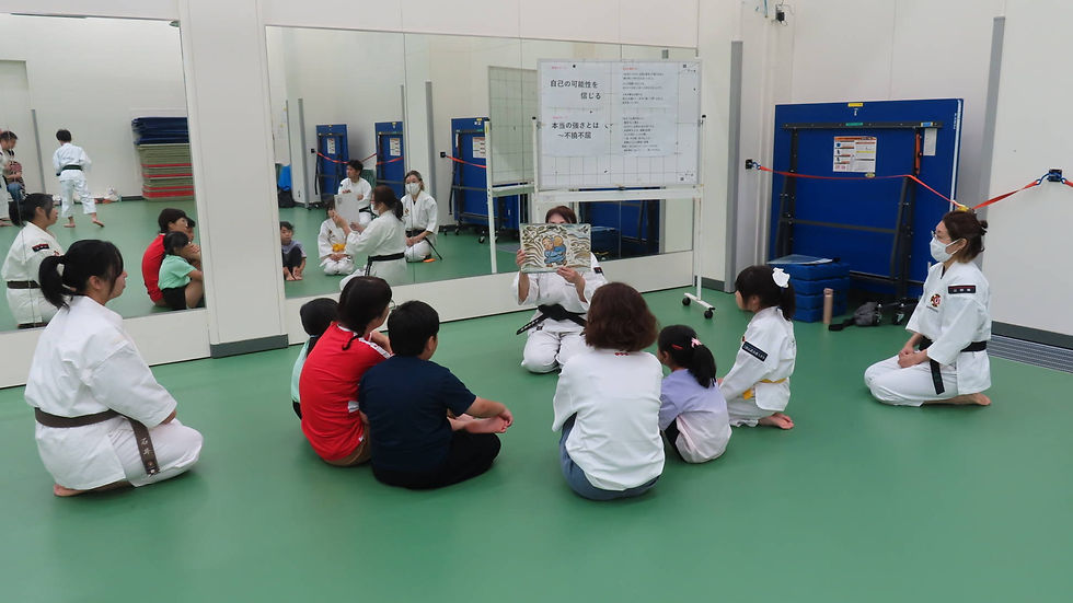 女性拳士が紙芝居を朗読し、子どもたちが静かに耳を傾けている様子。