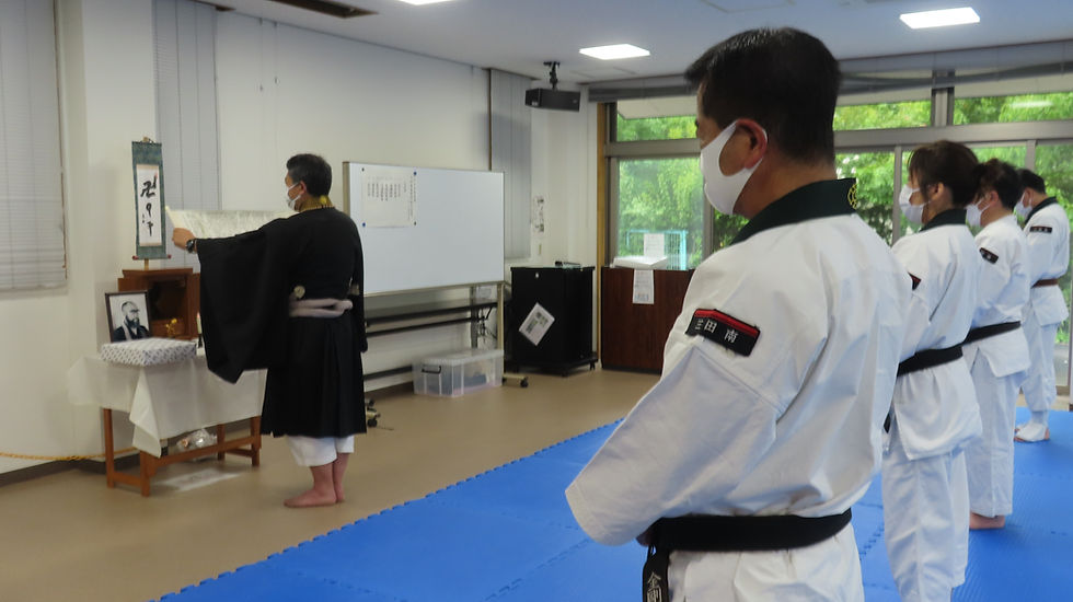 開祖忌法要で導師が教典を奉読し、後方で参列拳士が整列している様子(2023 年)