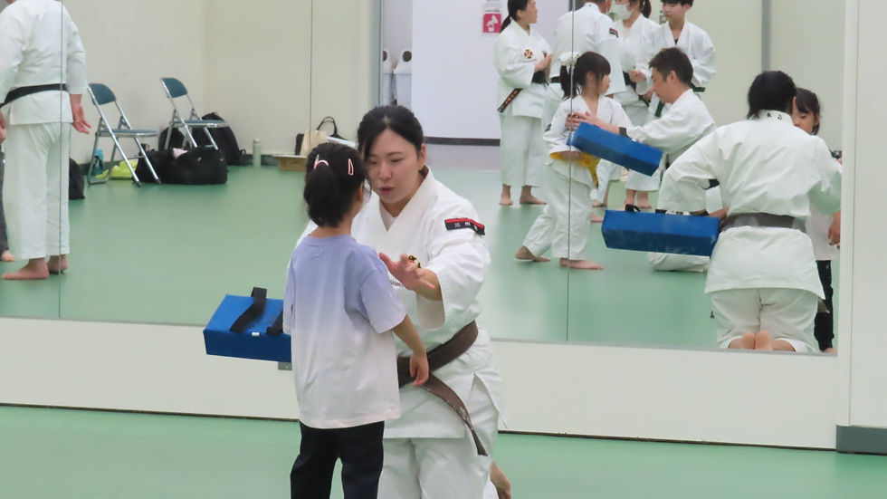 少女が拳士にミット打ちを教わる場面。鏡に指導の様子が映っている。