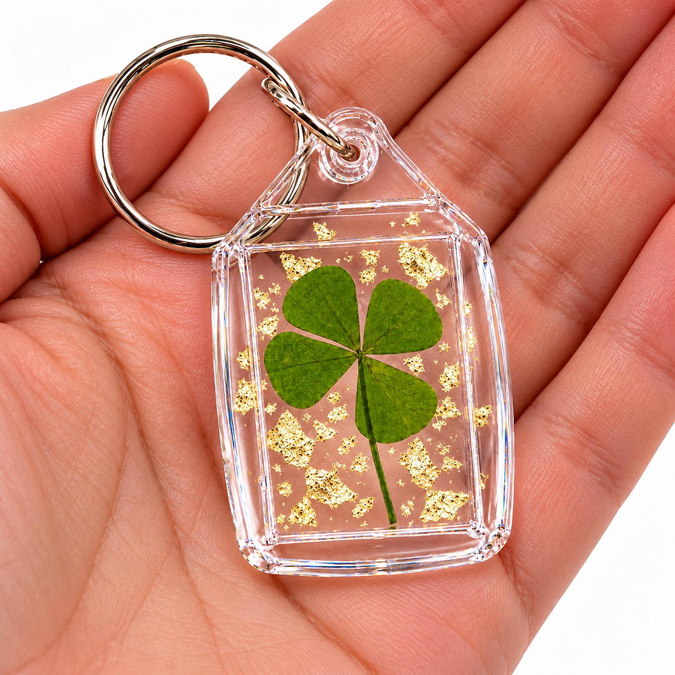 Porte-clés transparent avec véritable trèfle à 4 feuilles et paillettes dorées, présenté dans la paume d’une main.