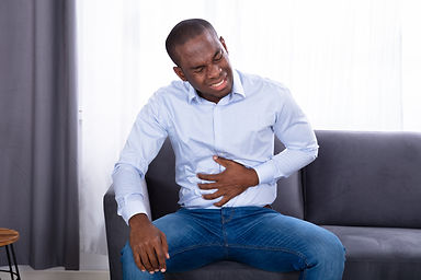 Close-up Of A Young African Man In Pain Holding His Stomach.jpg