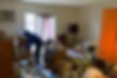 Person sorting through cluttered living room filled with papers.