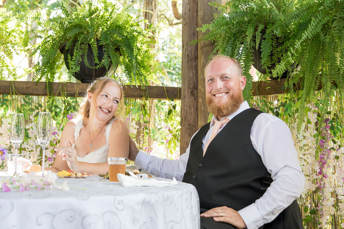 Bride and groom smiling at reception table in SWFL.