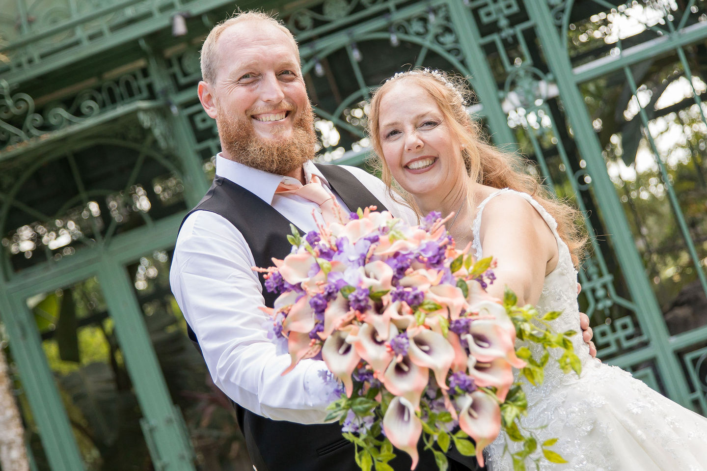 Happy bride and groom posing with bouquet in SWFL garden.