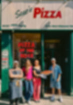 Four staff standing outside the store with a huge pizza