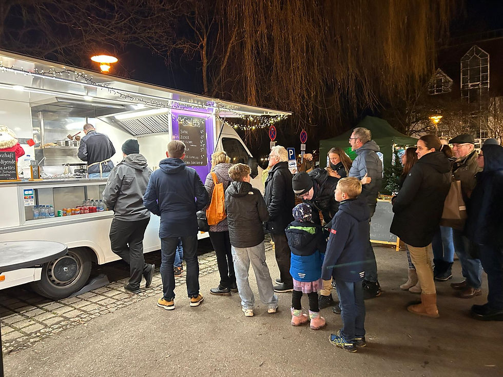 Gäste stehen abends am beleuchteten Rom Foodtruck und bestellen frische Crêpes.