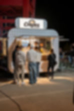 Kunden stehen Schlange vor dem beleuchteten Crêpes Kitchen Foodtruck am Abend