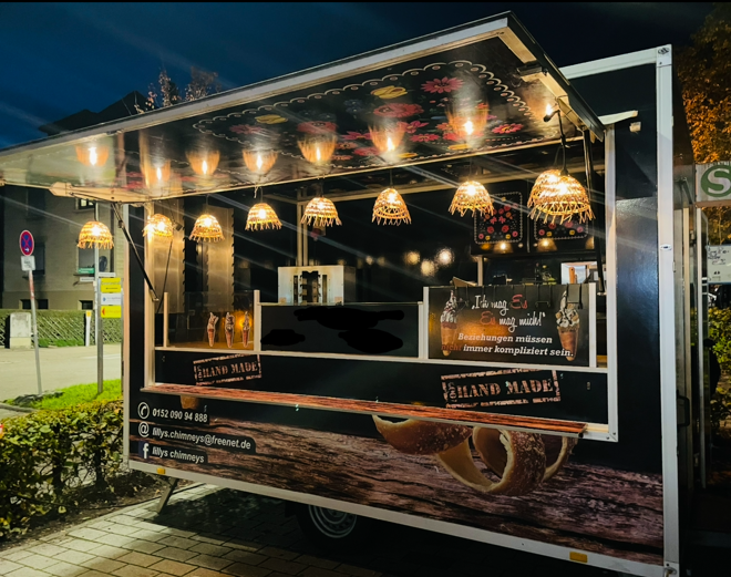 Beleuchteter Foodtruck am Abend mit geöffnetem Verkaufsfenster und Lampen von Lilly's Foodtrucks.