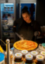 Mitarbeiterin bereitet frischen Crepe mit verschiedenen Zutaten im Crêpes Kitchen Foodtruck zu