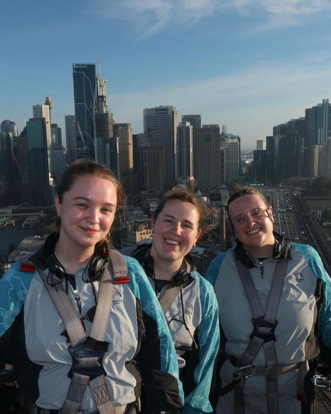 A group of people smiling in front of Sydney skyline.
