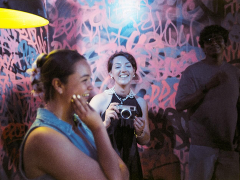 Two people smiling and talking at a colorful, graffiti-covered venue.