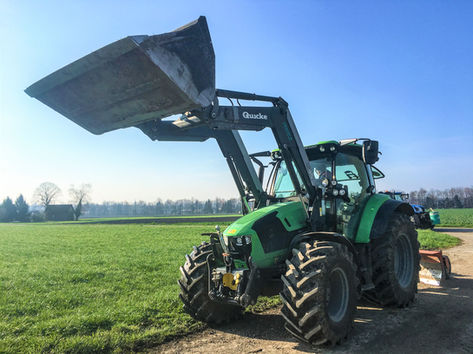 Grüner Traktor mit Schaufel auf Feld