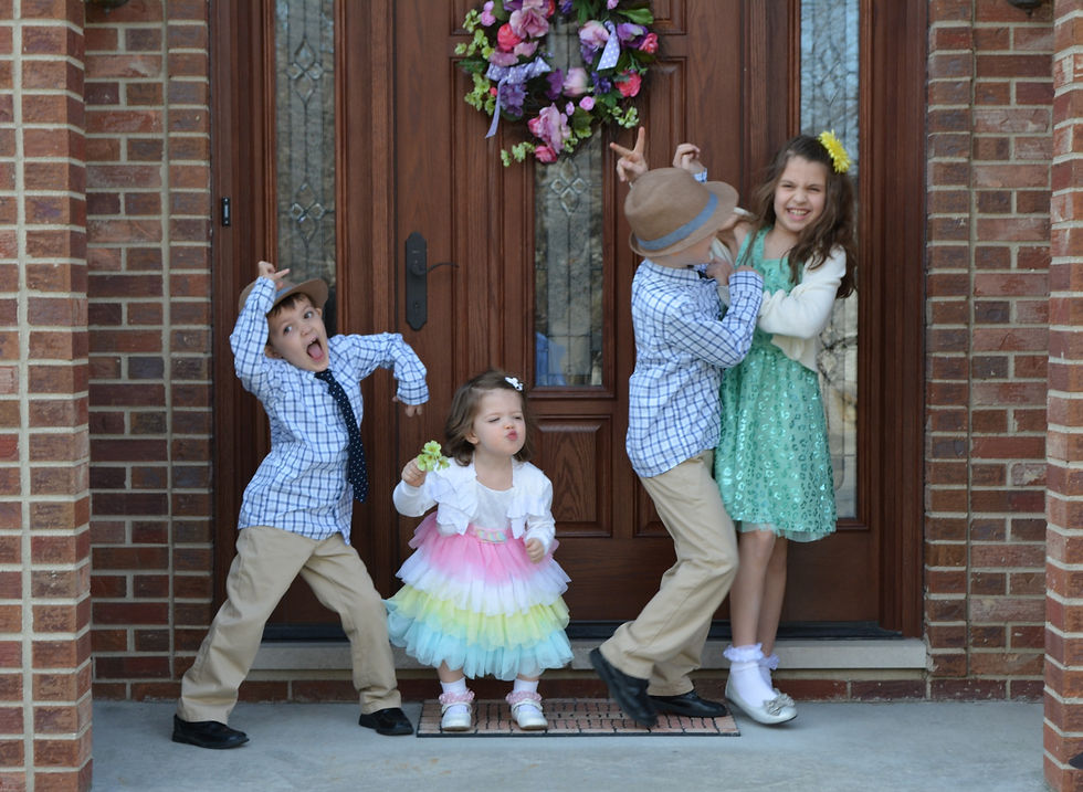Four children in fancy Easter clothes being silly on a porch.