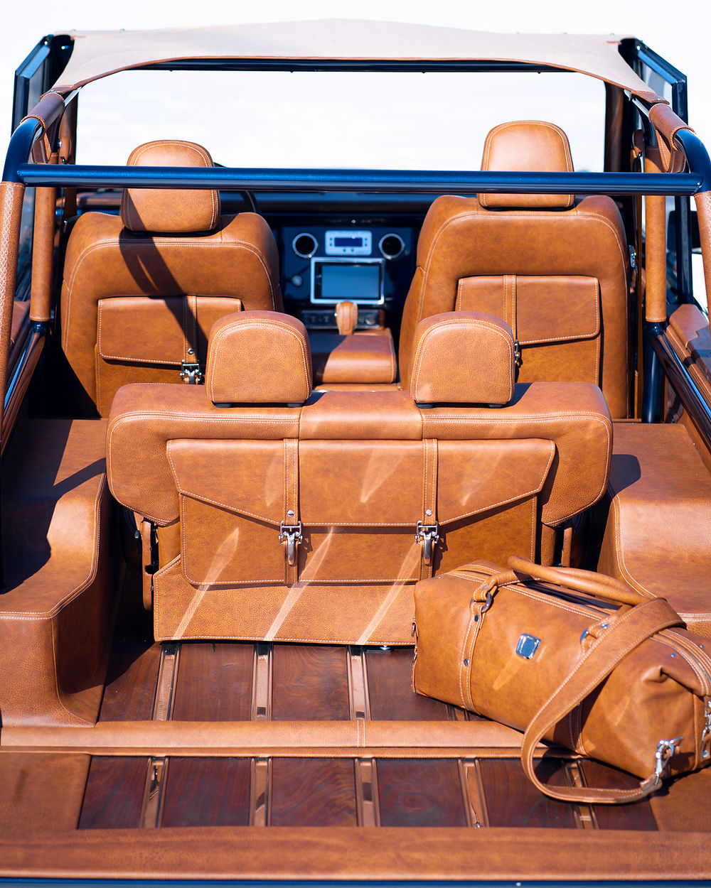 Rear interior of a custom 1977 Bronco with tan leather seats and wood floor
