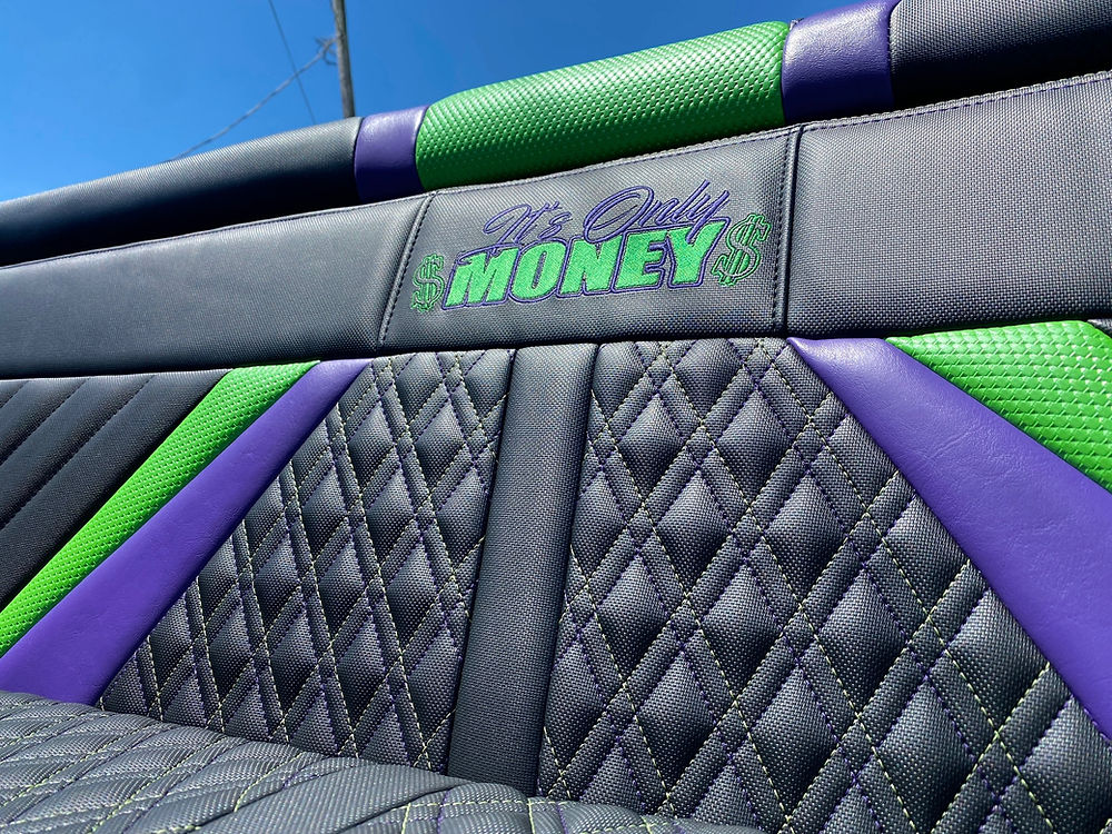 Custom black, purple, green car seat with 'IT'S ONLY MONEY$' text