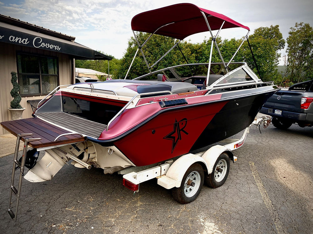Red and black marine boat with canopy on trailer