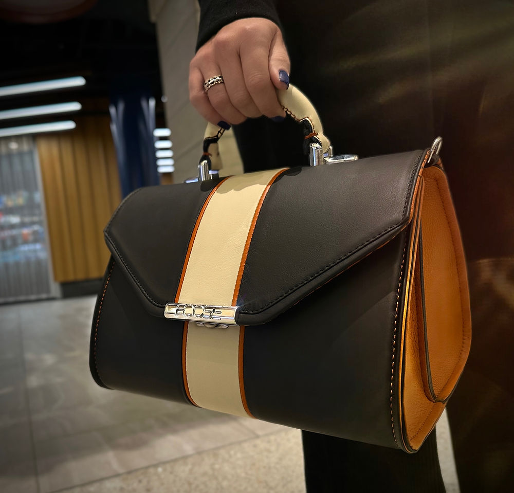 Hand holding a bespoke leather bag with cream stripe