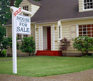 An image of a house with a for sale sign out front