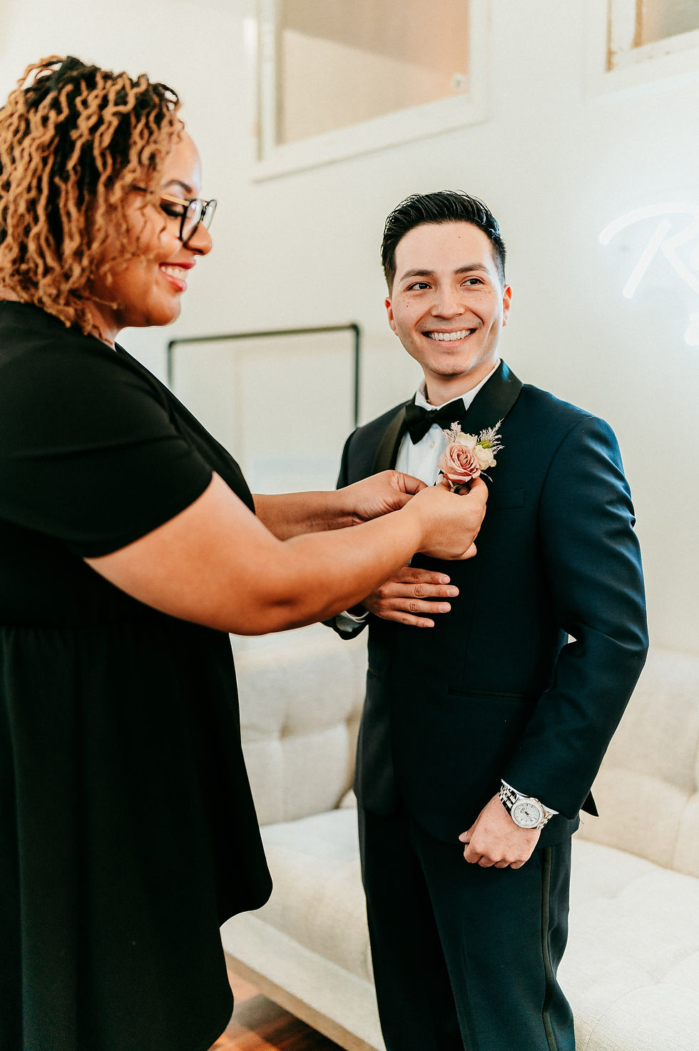 wedding coordinator adjusting boutonniere of groom
