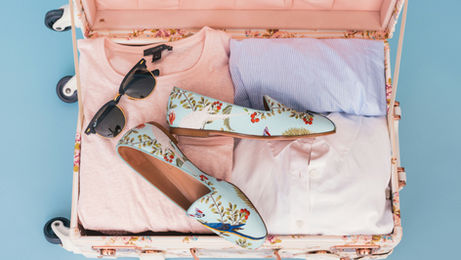 A suitcase packed with clothes and shoes, symbolizing preparation for a holiday trip.