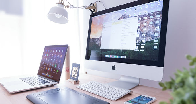 A desk featuring a computer, laptop, and phone, illustrating technology used for teaching ESL speaking.