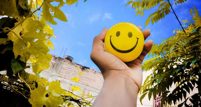 Individual displaying a smiley face in front of a tree, representing happiness for an ESL idioms lesson plan.
