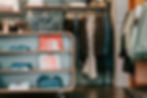 Clothing store interior with neatly folded clothes in a wooden shelf.