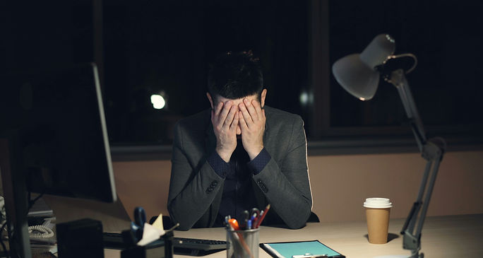 A man at his desk, head in hands, showing signs of stress and burnout.