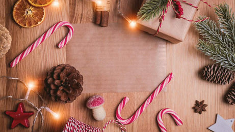 Colourful Christmas decorations on a wooden table beside a festive paper, celebrating holiday traditions.
