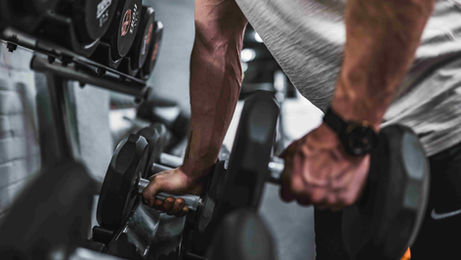 A man lifts weights in a gym, demonstrating consistency and focus for an ESL lesson plan.
