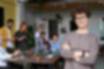 A woman with glasses addresses a group, guiding them through a leadership ESL lesson plan.