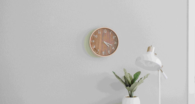 A minimalist white desk featuring a clock, set up for an ESL lesson plan on minimalism.