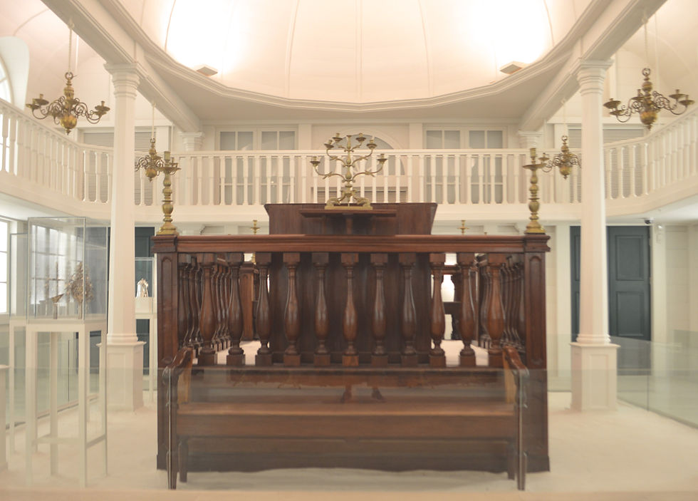 The bima, or teva, was made in Paramaribo in the 1800s. The women'a gallery of the Tzedek v'Shalom gallery is supported by 12 columns.