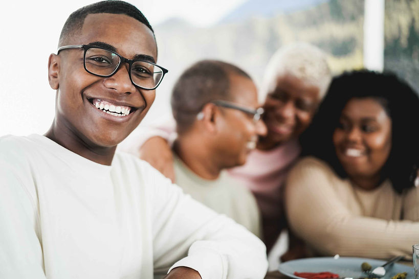 happy-black-young-man-eating-lunch-with-his-family-FZ47BC5.jpg