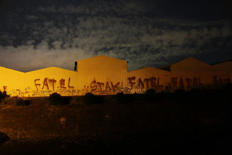 Yellow buildings with FATEL graffiti at night