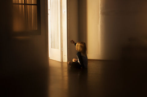 Child on floor, reaching for light from open doorway