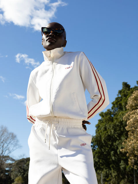 Person in white tracksuit with red stripes and sunglasses