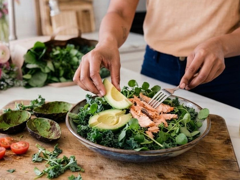 Midlife Woman Preparing Blood Sugar-Friendly High Protein Salad With Avocado & Salmon On Mixed Greens