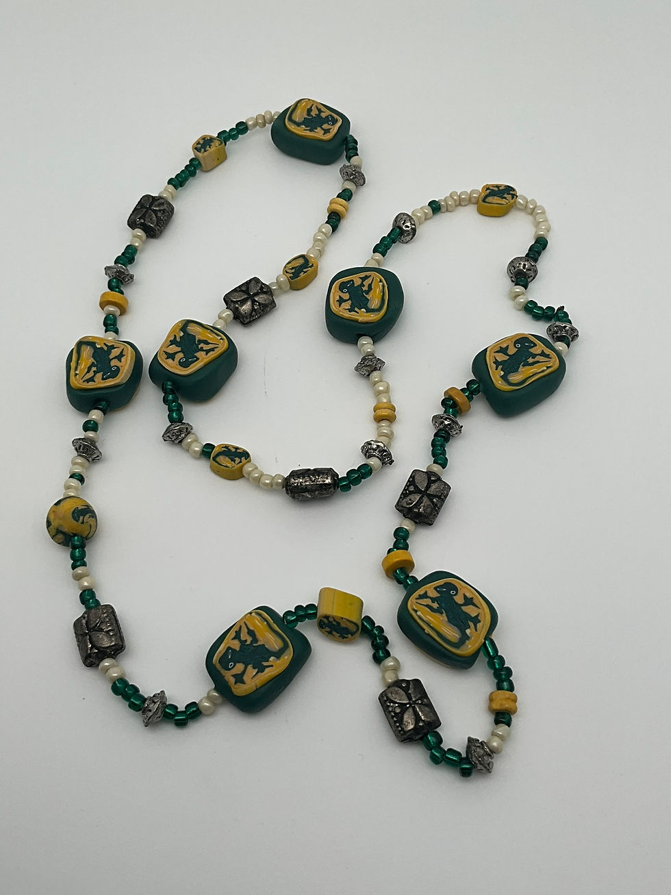Collar de caída larga con cuentas pequeñas y grandes, en tonos amarillo y verde y dibujo de lagartijas.
