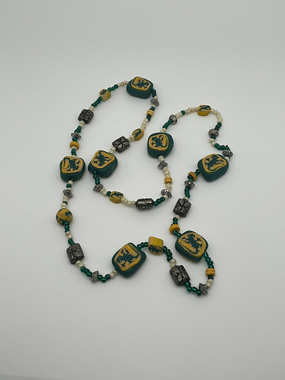 Collar de caída larga con cuentas pequeñas y grandes, en tonos amarillo y verde y dibujo de lagartijas.