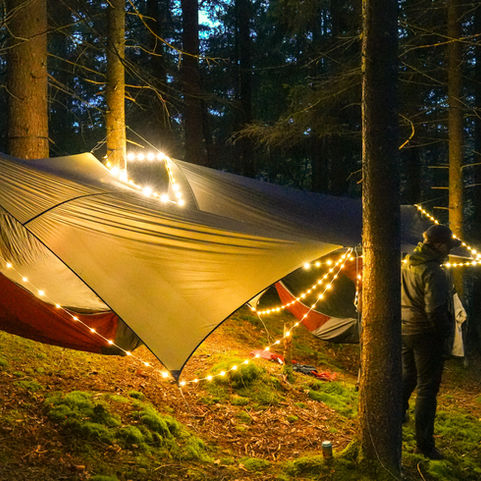 Hängmattor med ljusslingor i skogen