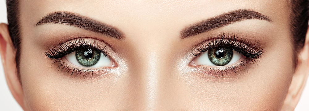 Close-up of two beautiful, open brown eyes with perfectly shaped eyebrows.