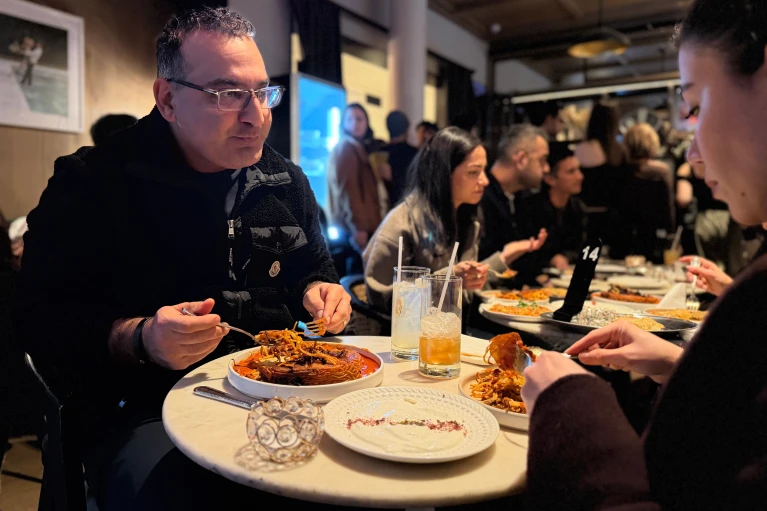 Kayvon Pourmirzaie and his wife, Behnaz Almazi, eat a tahdig-like pasta dish, based on a classic Iranian crispy rice dish, during a Persian pop-up dinner to celebrate Nowruz in New York on Saturday, March 14,2026.(AP 	Photo/ J.M.Hirsch)