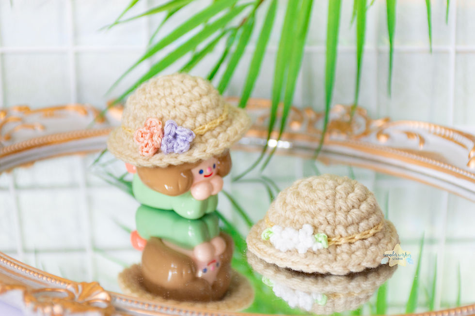 a toy modelling a tan hat with orange and purple flowers next to a second tan hat with small white flowers