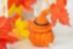 A toy pig modelling an orange hat and orange pumpkin clothes back view