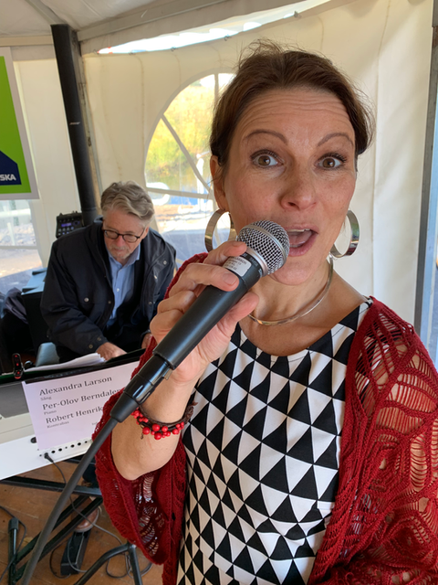 En bild av Alexandra som står och sjunger med en mikrofon i handen.